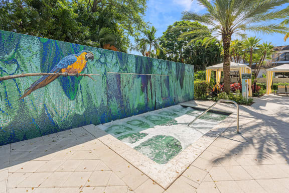 a mural of a parrot on a fence next to a fountain