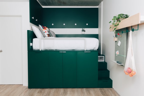 a green bedroom with a bed in a room with green cabinets