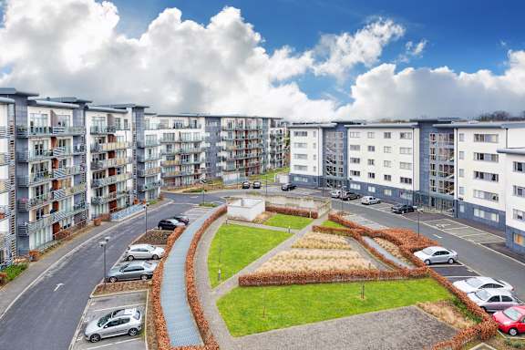 a view of an apartment complex with cars parked in front of it