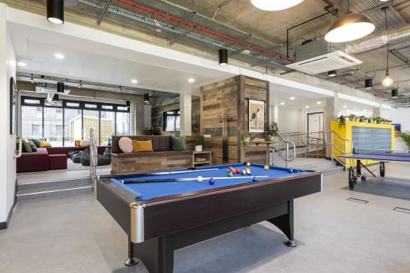a games room with a pool table in the middle