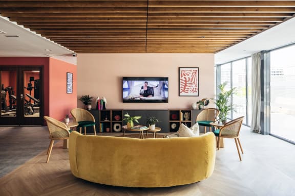 a living room with a yellow couch and chairs and a television