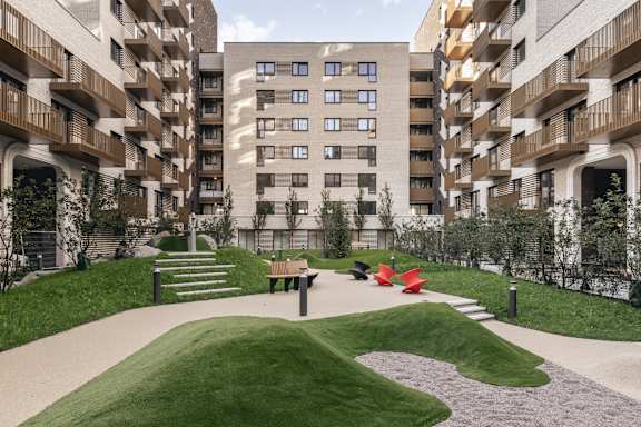 A grassy area in front of apartment buildings with a bench and steps.