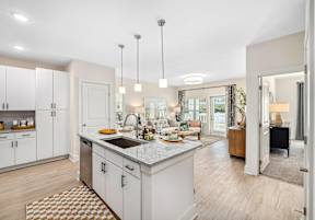 A well-lit, modern kitchen with a dining area in the background.