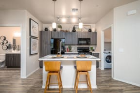 a kitchen with a large island with two stools in front of it