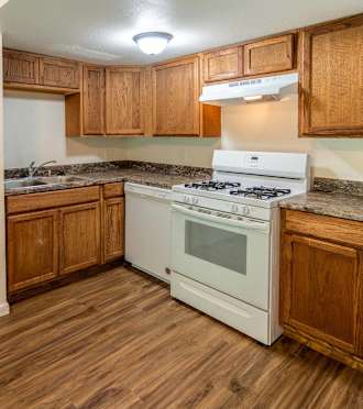 A kitchen with a white fridge, white stove and wooden cabinets.