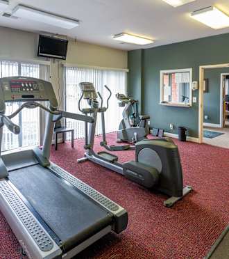 A treadmill, elliptical trainer and a stationary bike are in a gym.