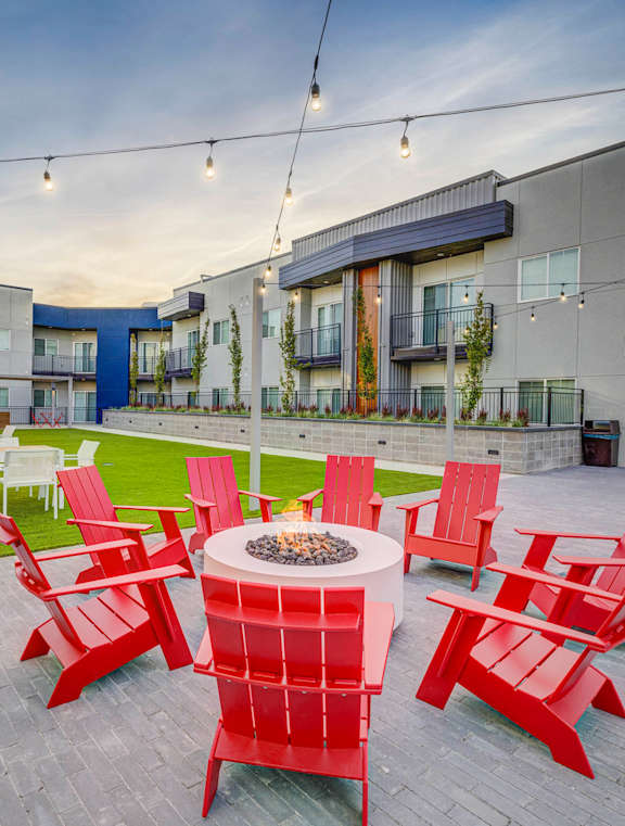 an outdoor patio with red chairs and a fire pit