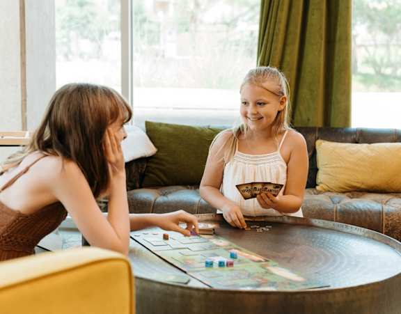 Two girls playing a board game on a table.