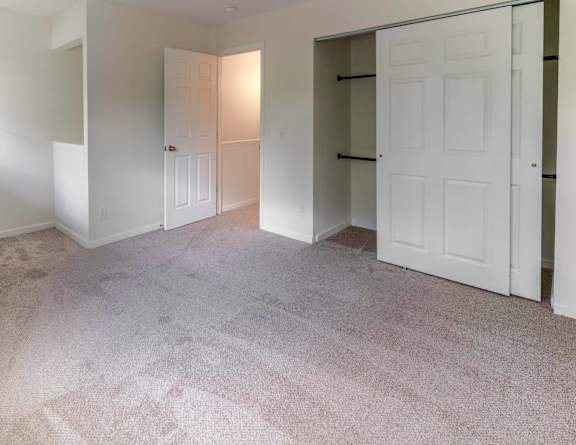A bedroom with a bed, a plant, and a closet at Arbor Pointe Townhomes Apartments, Battle Creek, MI