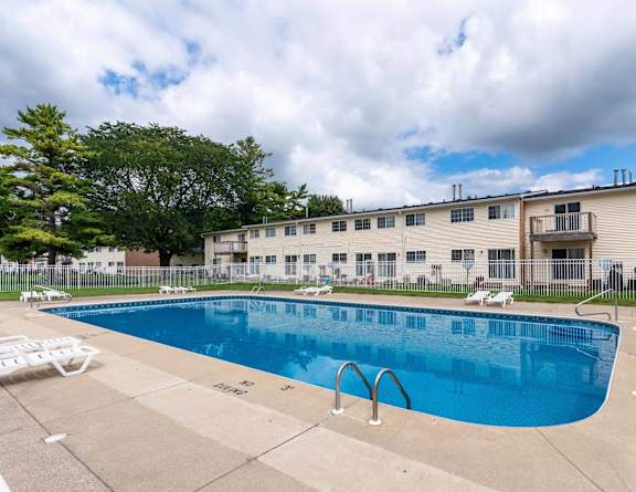 A swimming pool in front of a building with a cloudy sky at Arbor Pointe Townhomes Apartments, Michigan