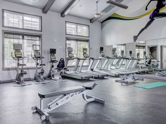 A gym with treadmills, elliptical machines, and a weight bench.