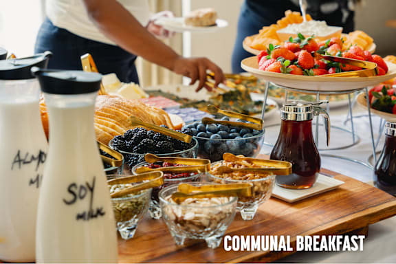 A communal breakfast table with various foods and drinks.