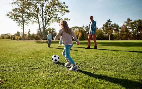 A girl is playing soccer on a sunny day.