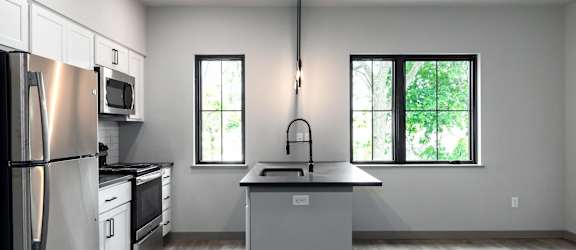A modern kitchen with wooden shelves and black countertops.
