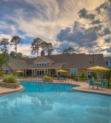 Exterior view of resort-style swimming pool with view of clubhouse at Lullwater at Blair Stone apartments for rent