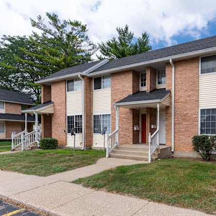A brick apartment building with a red door and a small porch.