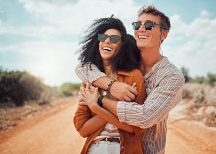 A couple is hugging each other on a dirt road.