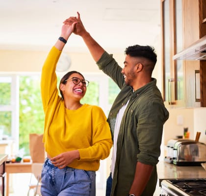 a couple holding their hands up in the air in the kitchen