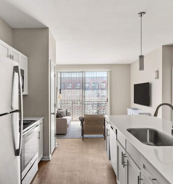 A modern kitchen with a refrigerator, sink, and a bowl of apples on the counter.