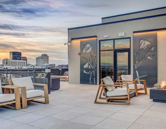a roof deck with chairs and a view of the city