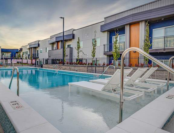 apartments with a pool and lounge chairs at dusk