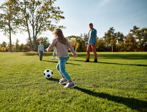 A girl is playing soccer on a sunny day.