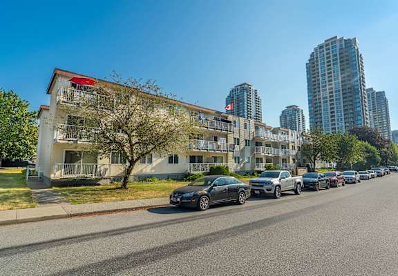 A row of cars parked on the side of a road in front of a building.