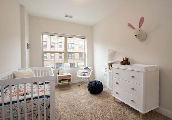 a nursery with a crib and a dresser and a window