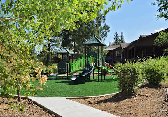 a playground with a swing set in front of a house