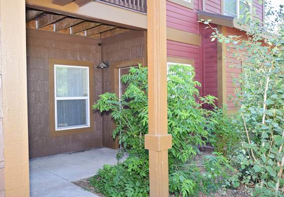 a covered porch in front of a house with plants