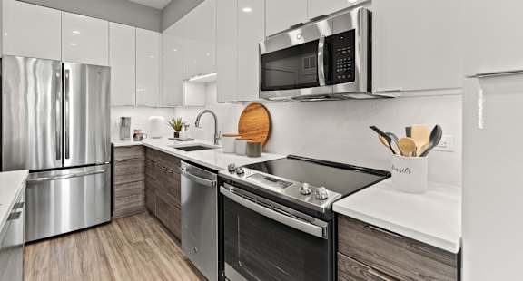 A modern kitchen with stainless steel appliances and wooden flooring.