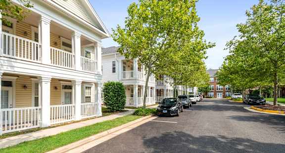 A street view of a residential area with cars parked on the side.