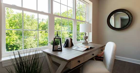 a home office with a large window and a desk with a white chair