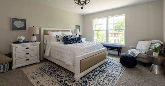 a bedroom with a white bed and a blue and white rug