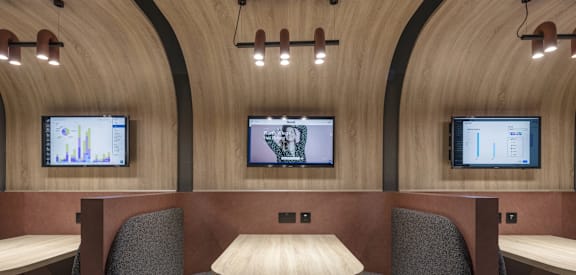 a meeting room with a table and chairs and televisions on the wall