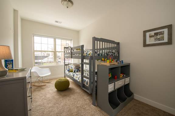 a bedroom with bunk beds and a desk and a window
