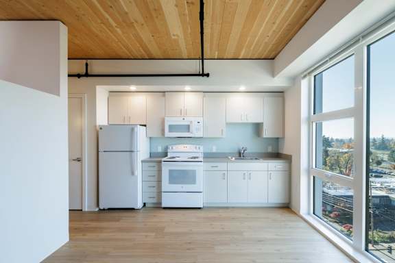 A modern kitchen with white appliances and wooden floors.