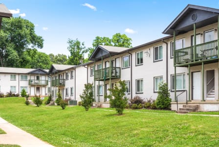 a row of apartment buildings with green grass and trees