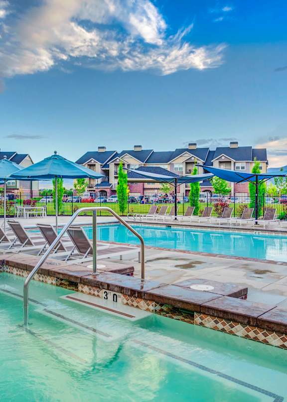 A large outdoor swimming pool with lounge chairs and umbrellas.