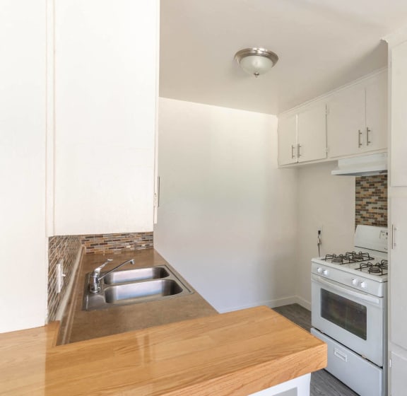 a kitchen with white appliances and a wooden counter top