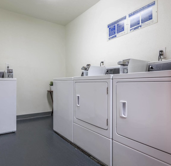 a laundry room with four washers and dryers in it