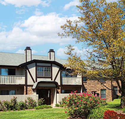 an apartment building with a lawn and flowering plants