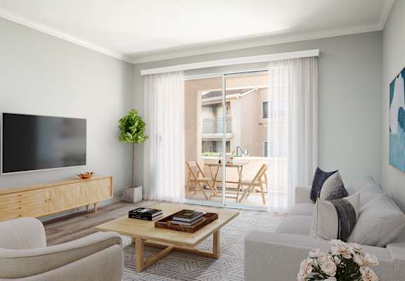 A living room with a flat screen TV, a wooden cabinet, a sofa, a coffee table, and a balcony with chairs.