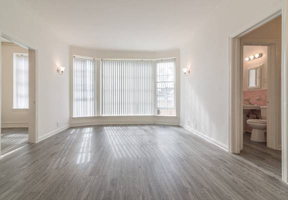 an empty living room with a large window and a bathroom