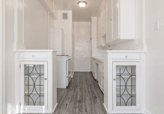 a white kitchen with white cabinets and a wood floor