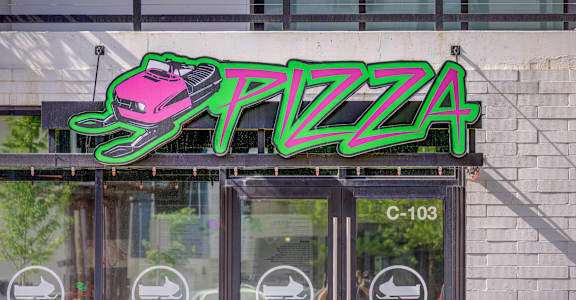 a neon sign that reads pizza on top of a building
