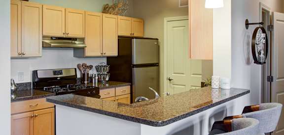 A kitchen with a granite countertop and wooden cabinets.
