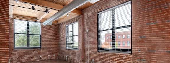 an empty living room with brick walls and wood floors