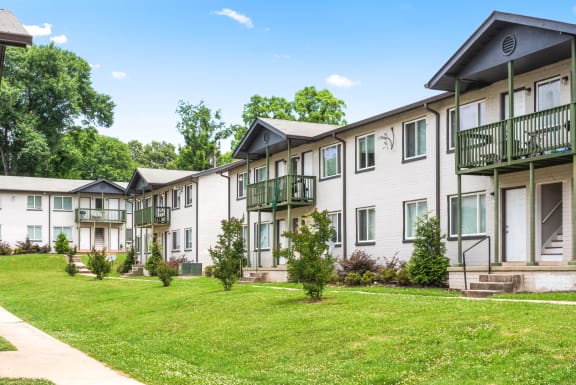 a row of apartment buildings with green grass and trees