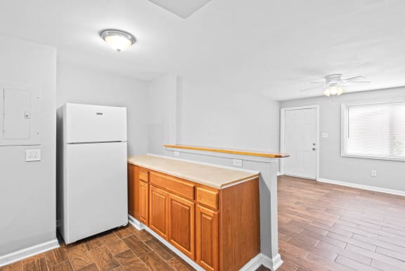 an empty kitchen with a refrigerator and wooden cabinets